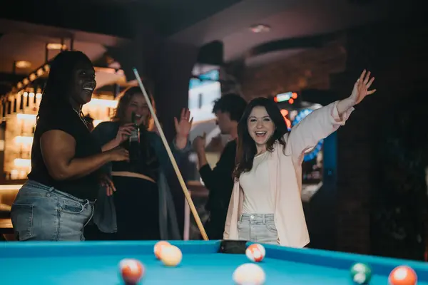 stock image A group of friends enjoying a fun-filled evening playing billiards in a cozy bar setting, sharing laughs and good times together.