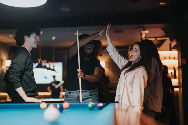 stock image Joy fills the air as friends celebrate a successful pool shot at a lively bar. Their evening out is captured in smiles, laughter, and high fives.