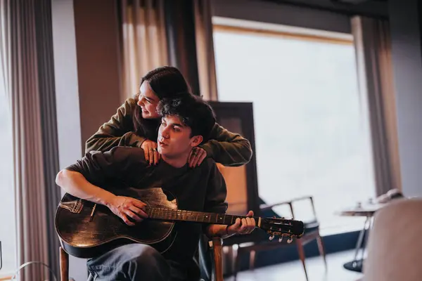 Mladý Pár Sdílí Něžné Objetí Při Hraní Kytaru Spolu Útulném — Stock fotografie
