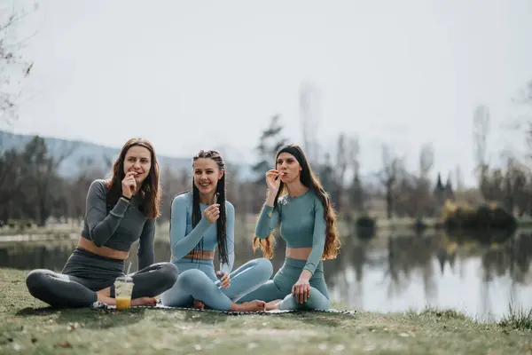 stock image Joyful female friends having a picnic with healthy snacks in a park, sharing a fun and relaxed moment together outdoors.