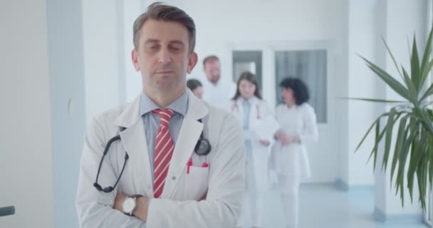 Zelfverzekerde Mannelijke Specialist Poserend Met Gevouwen Armen Kliniek Dokters Achtergrond — Stockvideo