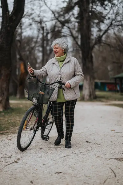 一个独立 成熟的女人和她的自行车站在公园里 体现了一种积极健康的生活方式 — 图库照片