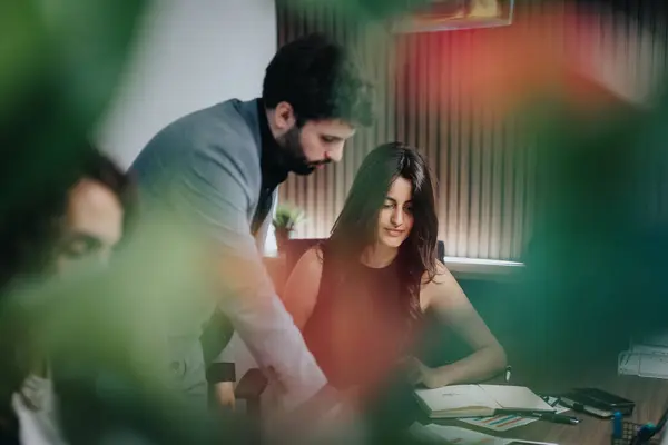 stock image A man and a woman, depicted as business colleagues, work attentively on documents at an office. The photo captures a serious and engaged work atmosphere.