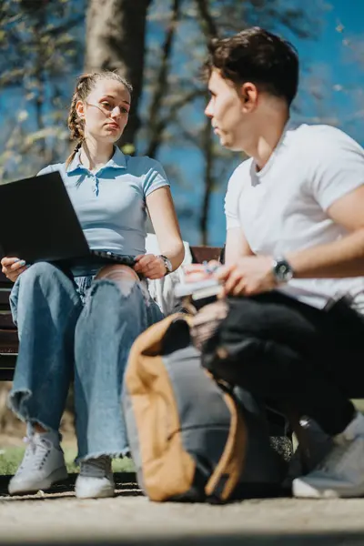 stock image Two friends sharing ideas while learning and enjoying the serenity of a park setting.