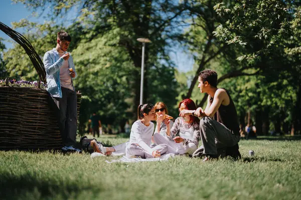 stock image A joyful gathering in the park featuring friends chatting and eating ice cream on a sunny, carefree day. Perfect scene of outdoor relaxation and enjoyment.