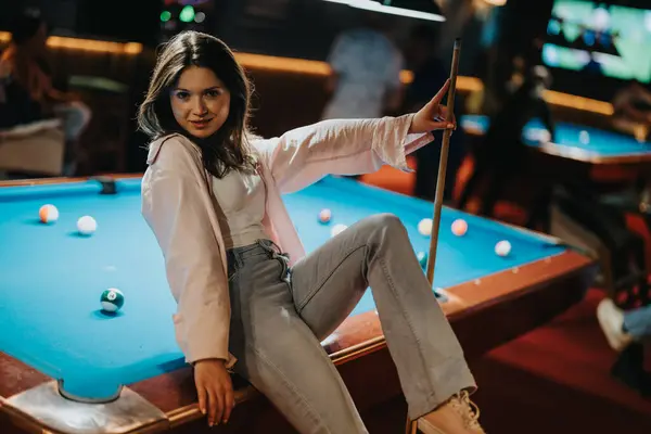 Young Woman Enjoys Game Billiards Striking Playful Pose Her Cue Imagem De Stock