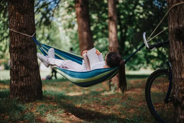 Young Woman Enjoys Quiet Reading Moment Hammock Surrounded Trees Serene Imagem De Stock