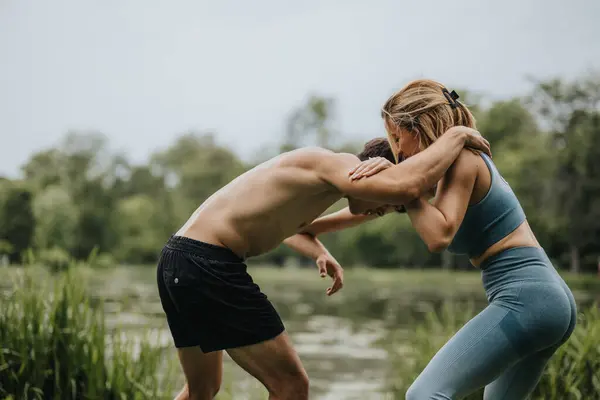 stock image Fitness couple participating in a wrestling exercise in a park. They are engaged in an intense workout session in a natural outdoor setting.