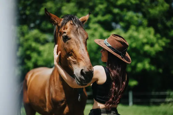 stock image A woman in a cowboy hat embracing her horse at the ranch, enjoying countryside life and forming a strong bond.