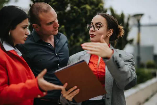 stock image Young, creative professionals in an outdoor business meeting, working on a project. Collaboration and discussion are central themes.