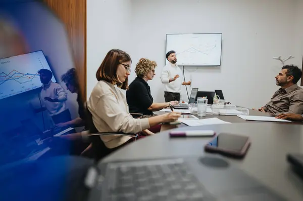 stock image A different aged group of business colleagues collaborating in a boardroom meeting, analyzing statistics and strategizing for success.