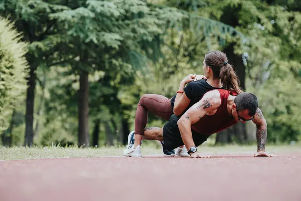 stock image A fit couple engages in a challenging exercise routine outdoors a strong man performs push-ups with his girlfriend on his back