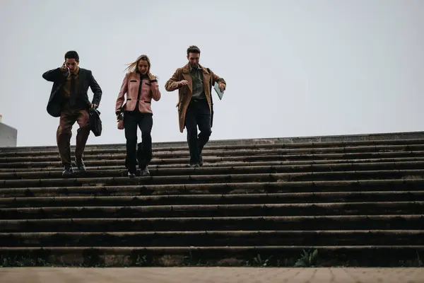 stock image Three business professionals in smart casual attire descending outdoor steps together, embodying teamwork and determination.