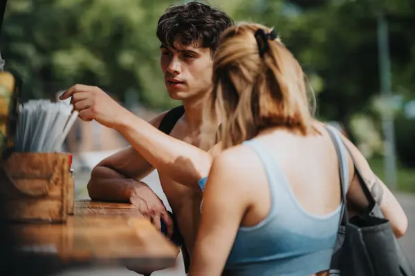 stock image Sports couple in casual athletic wear buying refreshing drinks at an outdoor stand after a vigorous training session.