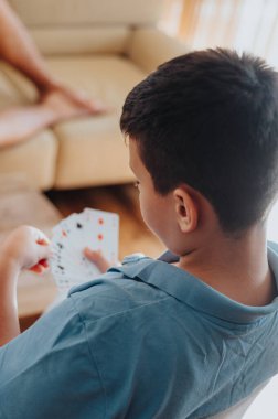 Boy enjoying a card game with family at home. Captures the essence of fun, relaxation, and togetherness. clipart