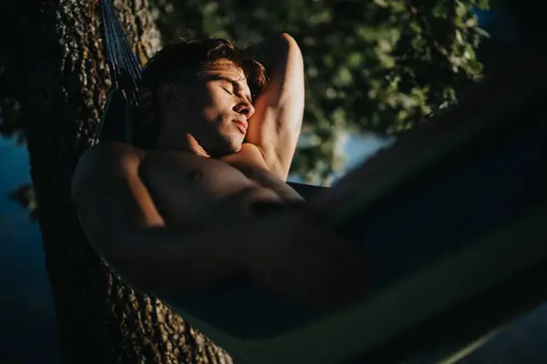 stock image A man relaxing on a hammock, enjoying a sunny summer day in nature. Peaceful moment outdoors.