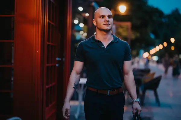 stock image Confident man walking at night in the city, showcasing business attire and an urban lifestyle. Street lights and busy environment in the background.