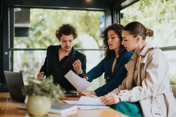 stock image Young business partners working remotely at an urban coffee bar, solving project tasks, analyzing reports, and creating new marketing strategies.