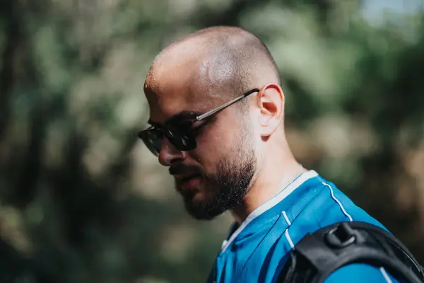 stock image Close-up of a young man in sunglasses and a blue shirt enjoying a sunny outdoor day, captured in a candid moment.