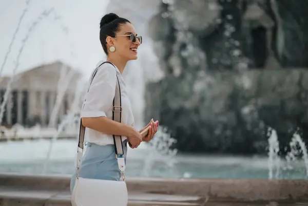 Stock image Smiling businesswoman enjoys a casual outdoor meeting in front of a fountain, embracing work-life balance and professional attire.