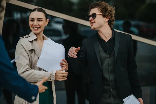 stock image Two business professionals engaging in a casual discussion while holding documents outside a modern office building.