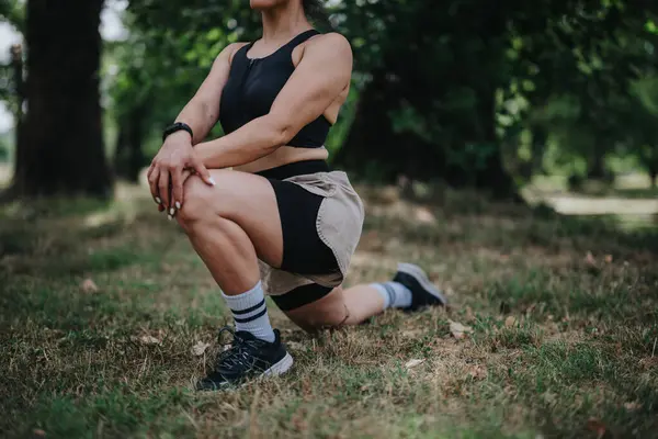 stock image Woman stretching in an outdoor park, wearing fitness attire, preparing for her daily workout session. Healthy lifestyle and fitness concept.