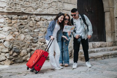 Three young tourists, friends hanging out and navigating with a map while exploring ancient town streets on a sunny vacation. clipart