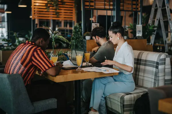 stock image Group of diverse professionals collaborating in a cozy coffee bar setting, discussing work and ideas during a business meeting.