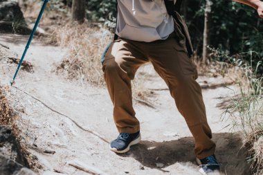 Close-up of a person hiking on a rugged forest trail during a sunny day, embodying fitness, adventure, and a healthy lifestyle. clipart