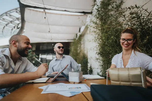 stock image Young business entrepreneurs strategizing and collaborating on a project. Teamwork for improvement and growth in an outdoor setting.