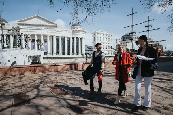 stock image Group of young professionals engaging in a business discussion outdoors with urban architecture in the background, strategizing for success.