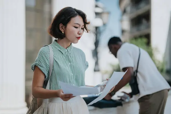 stock image Multicultural businesspeople in an outdoor city meeting, reviewing documents and discussing business strategy. Mixed-race professionals collaborating and sharing ideas in an urban setting.