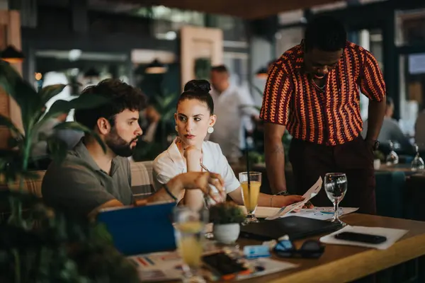 stock image Diverse group of colleagues engaged in a productive business meeting at a coffee bar, discussing documents and ideas.