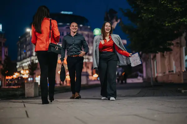 stock image Three young professionals engaging in a fun and creative outdoor business meeting in the city at night, discussing a project.