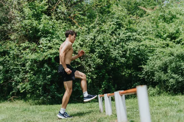 stock image Fit man performing fitness exercises outdoors amidst green nature. Showcasing active lifestyle and physical fitness.