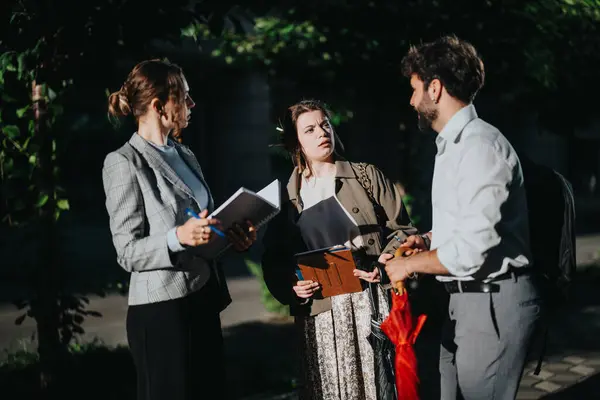 stock image Three young business associates brainstorming and discussing project ideas and strategies outdoors in an urban city setting.