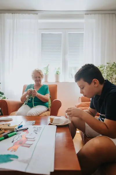 stock image A warm family scene with a grandmother knitting a vest as her young nephew enjoys a meal. The setting is a cozy living room filled with natural light, conveying warmth and togetherness.