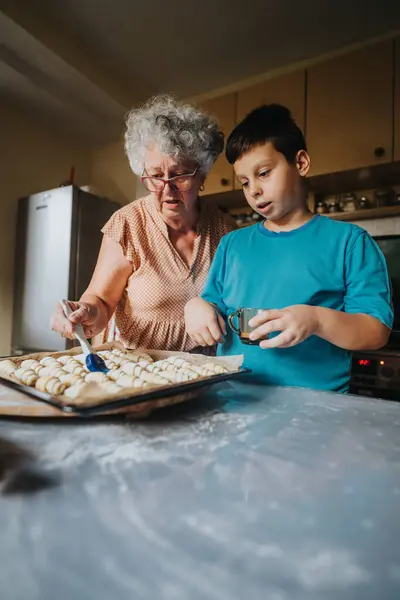 stock image A loving grandmother and her grandson bond while baking cookies in their cozy kitchen, highlighting family connection and culinary traditions.