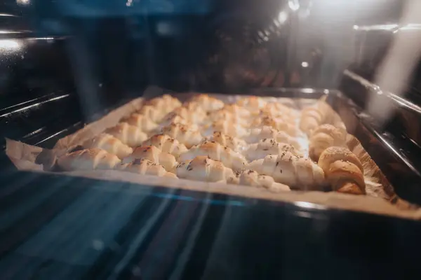 stock image Delicious homemade croissants baking to golden perfection in an oven. The flaky pastries fill the kitchen with a warm, inviting aroma, capturing the essence of home baking.