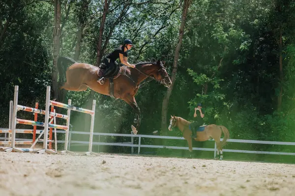 stock image Rider and horse in mid-air during an equestrian jumping competition, showcasing skill and determination in an outdoor arena.