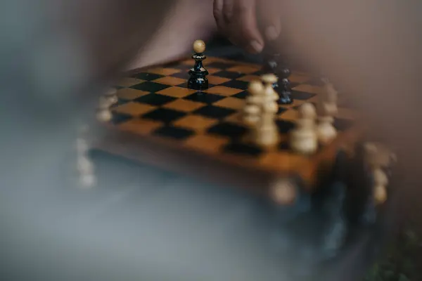 stock image Close-up of a hand moving a chess piece on a wooden board. The image conveys focus and strategy, captured in a serene setting with a misty effect.