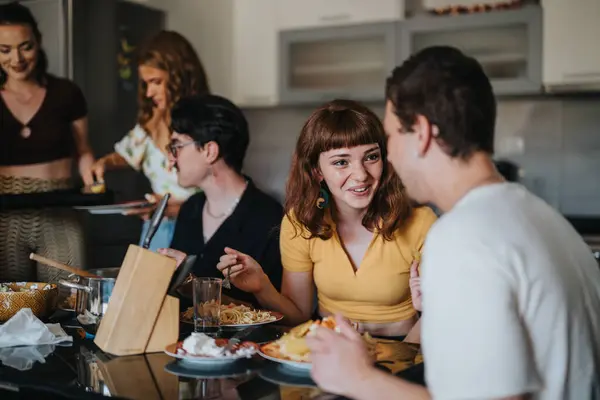 stock image A close-knit group of young adults sharing a meal and conversation in a cozy kitchen setting, highlighting friendship and togetherness.