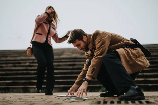 stock image A businessman in a coat drops papers with a businesswoman rushing by outdoors