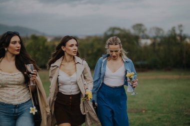 A group of three stylish women walking outdoors, holding drinks and flowers. The scenic background and relaxed atmosphere highlight friendship, leisure, and elegance. clipart