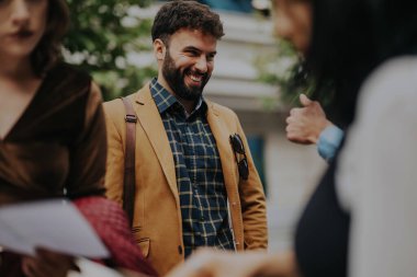 A cheerful businessman in a casual blazer and shirt is engaging with colleagues in a city environment. The image conveys a sense of friendly interaction and positive workplace communication. clipart