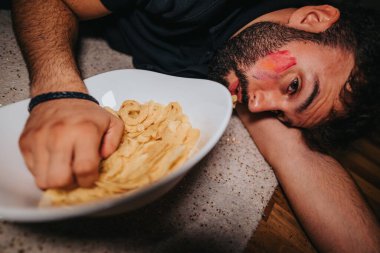 A man with colorful face paint lies beside a bowl of snacks, embodying a relaxed and tired vibe after a joyful celebration or party. clipart