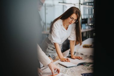 A team of people engaged in discussing architectural project plans in a modern office environment. They are focused on blueprints and paperwork, showcasing teamwork and collaboration in a business clipart