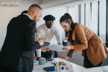 Diverse group of business professionals working together in an office setting, collaborating on ideas and discussing projects during a dynamic and focused team meeting. clipart