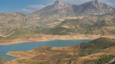 Dağların arasından akan bir dağ nehri. Arkaplanda bulutlu mavi bir gökyüzü..