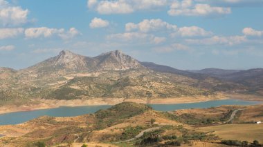 Dağların arasından akan bir dağ nehri. Arkaplanda bulutlu mavi bir gökyüzü..